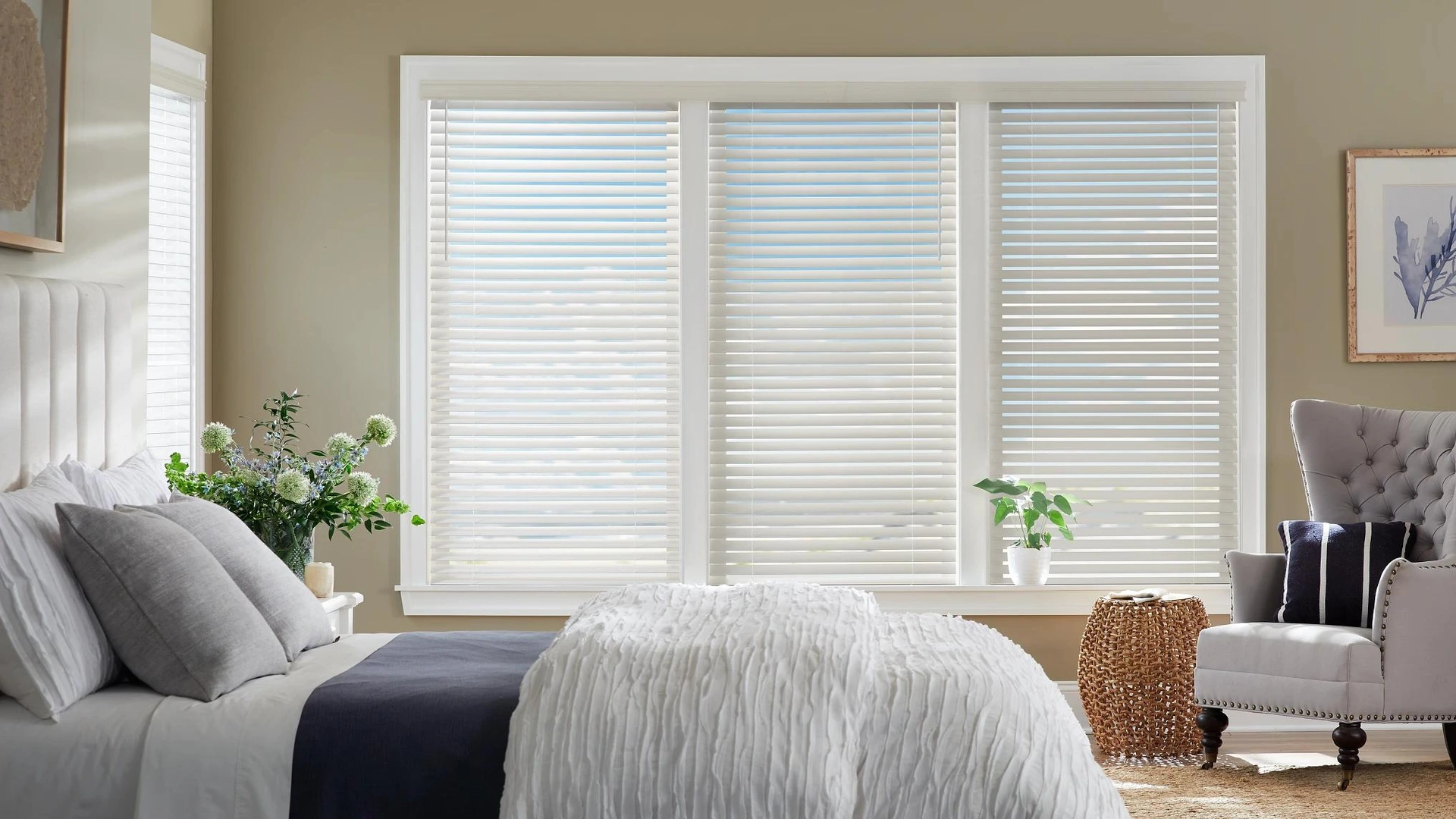 White Alta wood blinds behind a bed and sitting area.