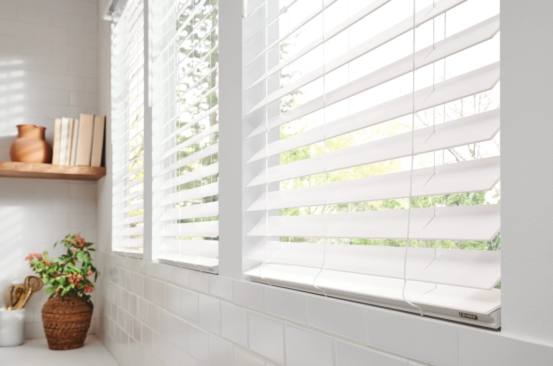 Close-up of pale Graber faux-wood slats with daylight behind them.