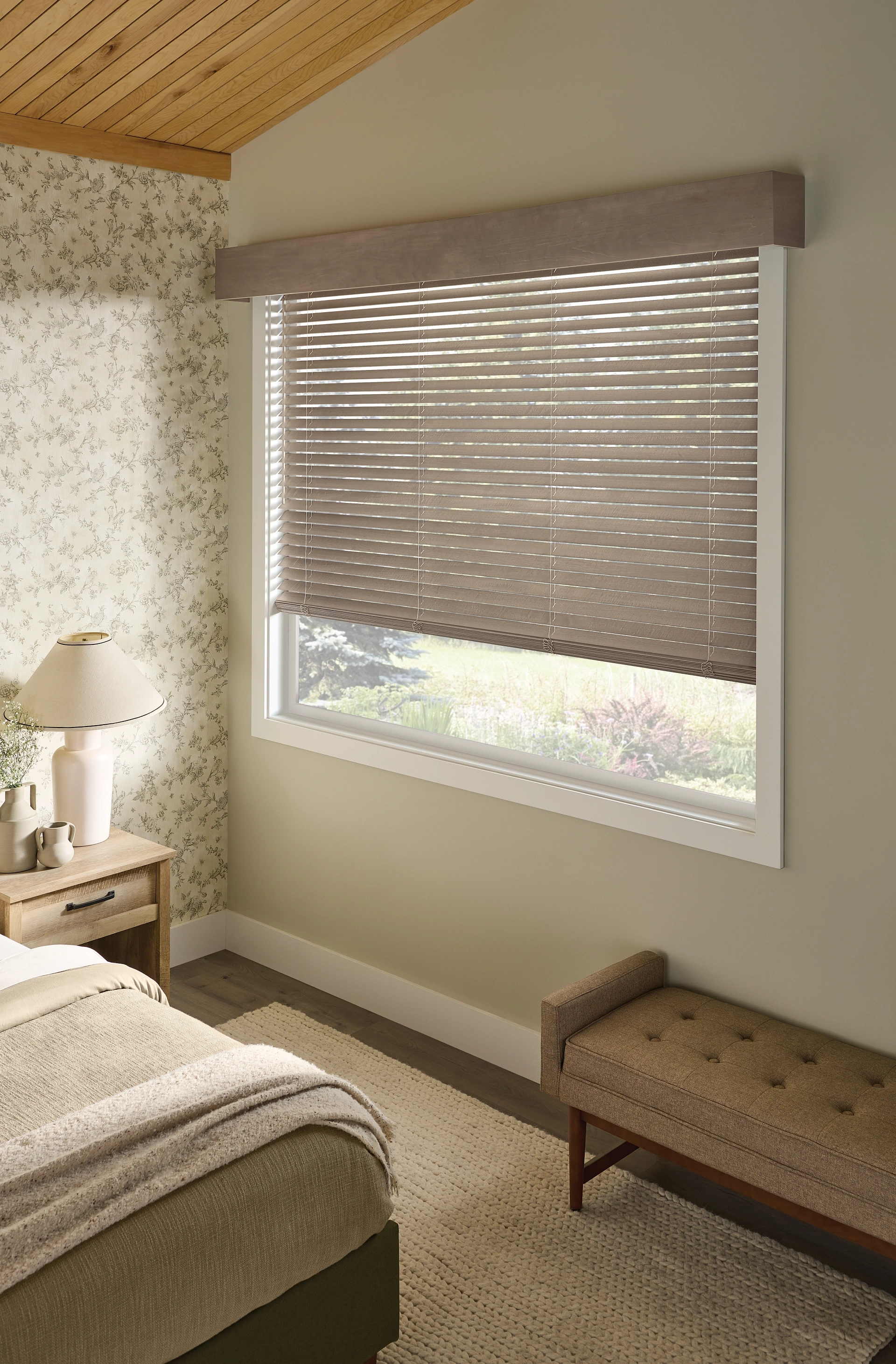 Graber wood blind with a matching cornice beside a bed.