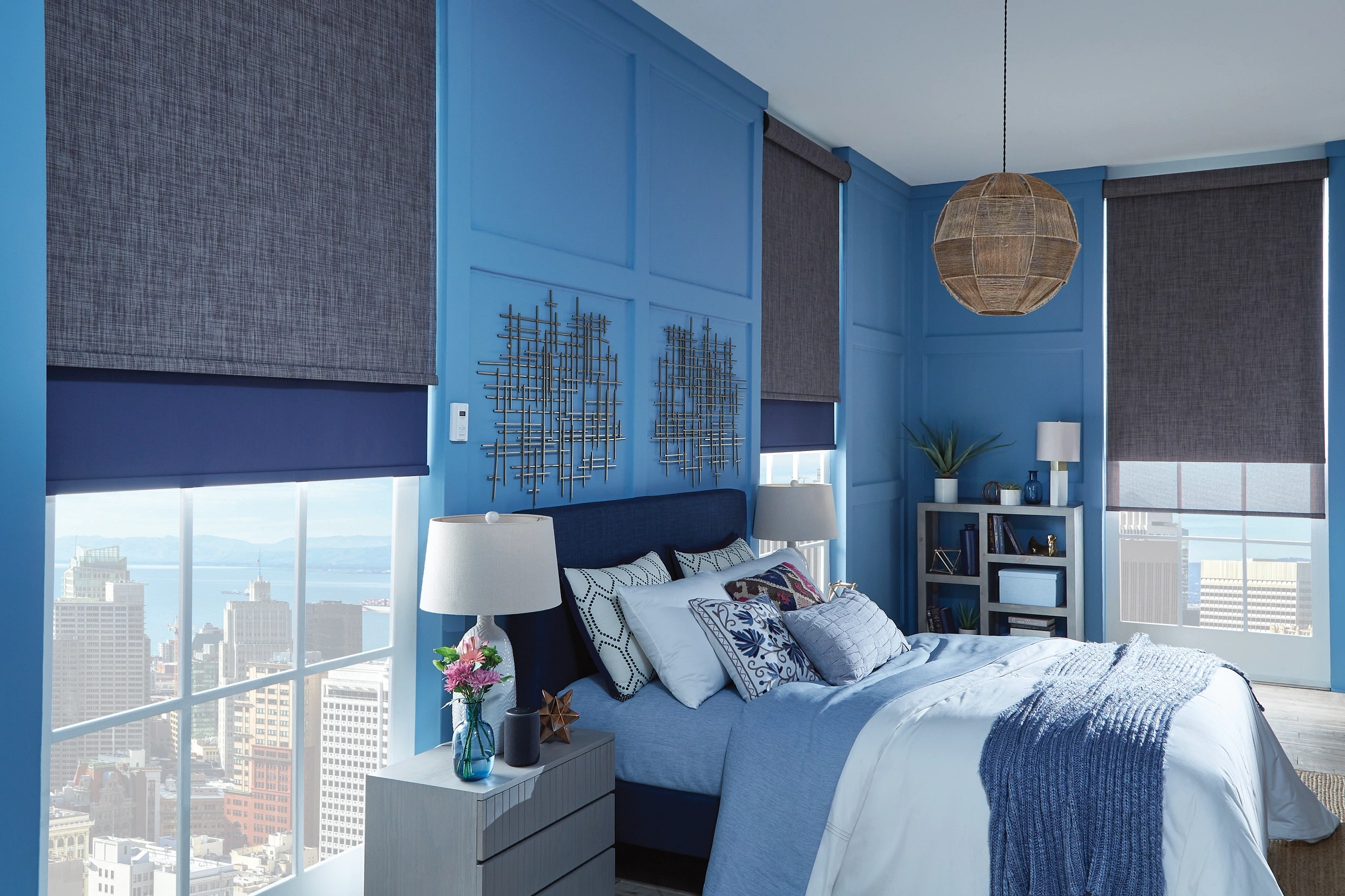Motorized Graber dual roller shades in a modern blue bedroom with charcoal textured fabric and navy blackout layers, custom window treatments.