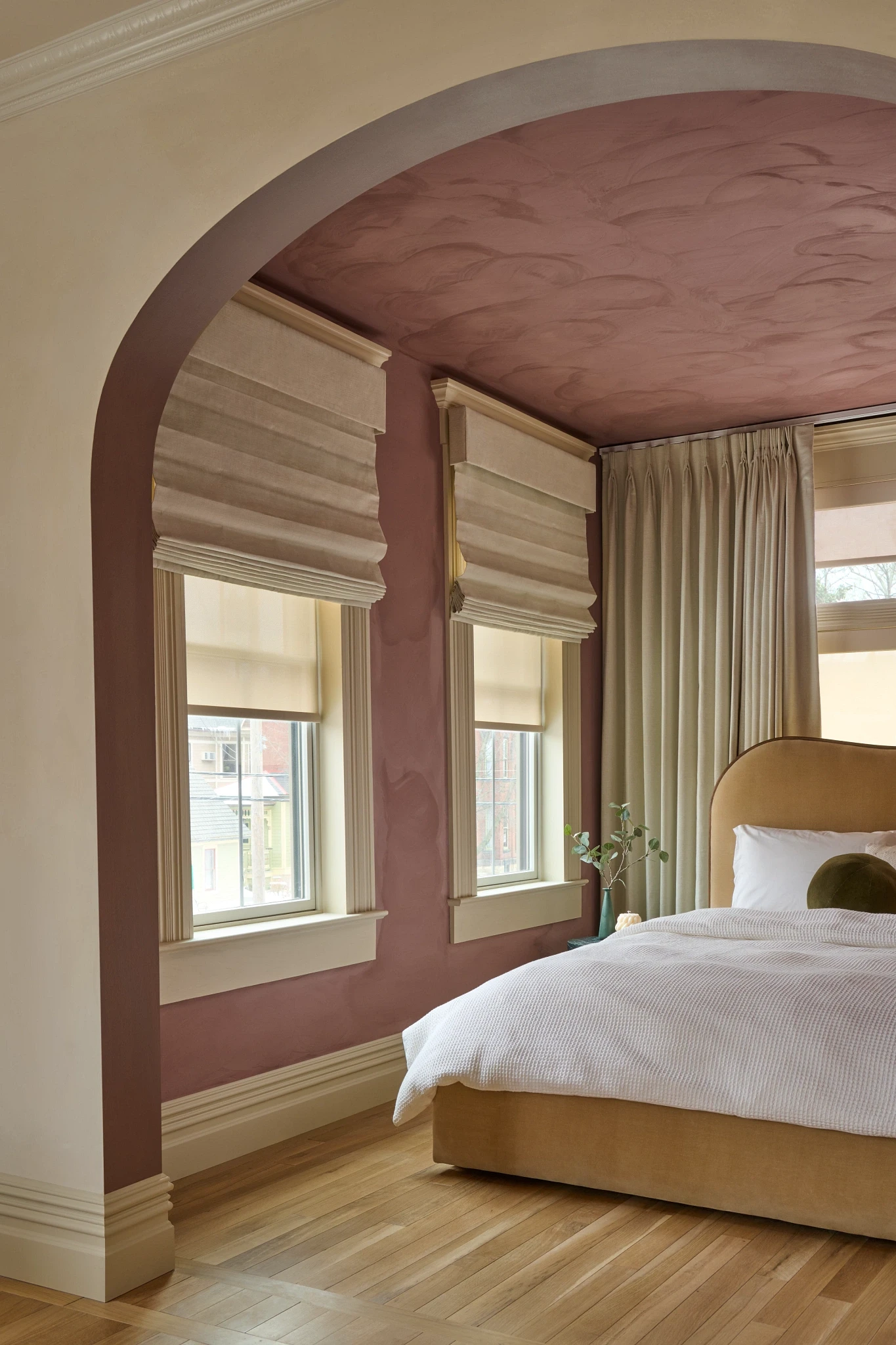 Graber Tailored Roman shades and drapery layered with solar shades in a bedroom.